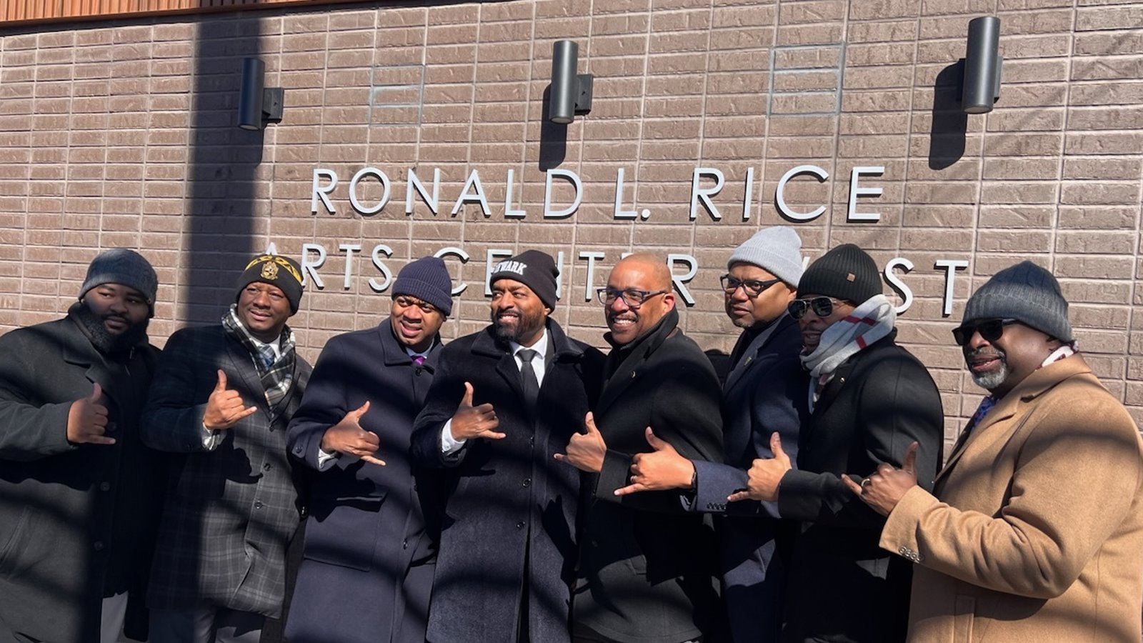A group of men in winter coats outside the Newark arts center named for Senator Ronald L. Rice
