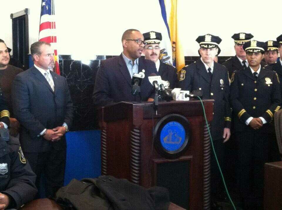 Ronald C. Rice speaking at a podium beside uniformed police officers
